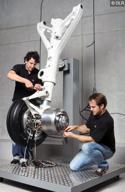 2 Mechaniker die an einem Radnabenantrieb eines Flugzeug-Bugfahrwerks arbeiten.